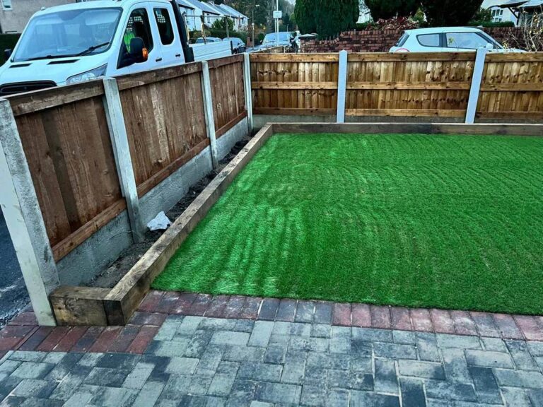 Artificial grass in a fenced garden with block paving
