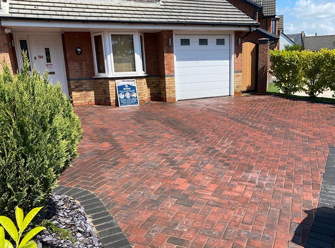 Red block paved driveway in front of a garage