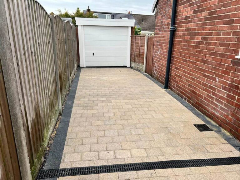 Buff block paved path with a drainage channel to a garage