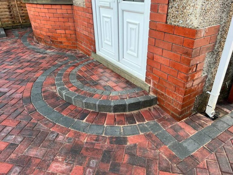 Curved block paved step at a front door with a herringbone driveway