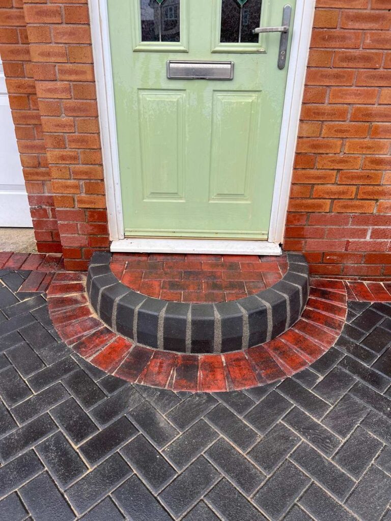 Curved block step at a front door with herringbone paving