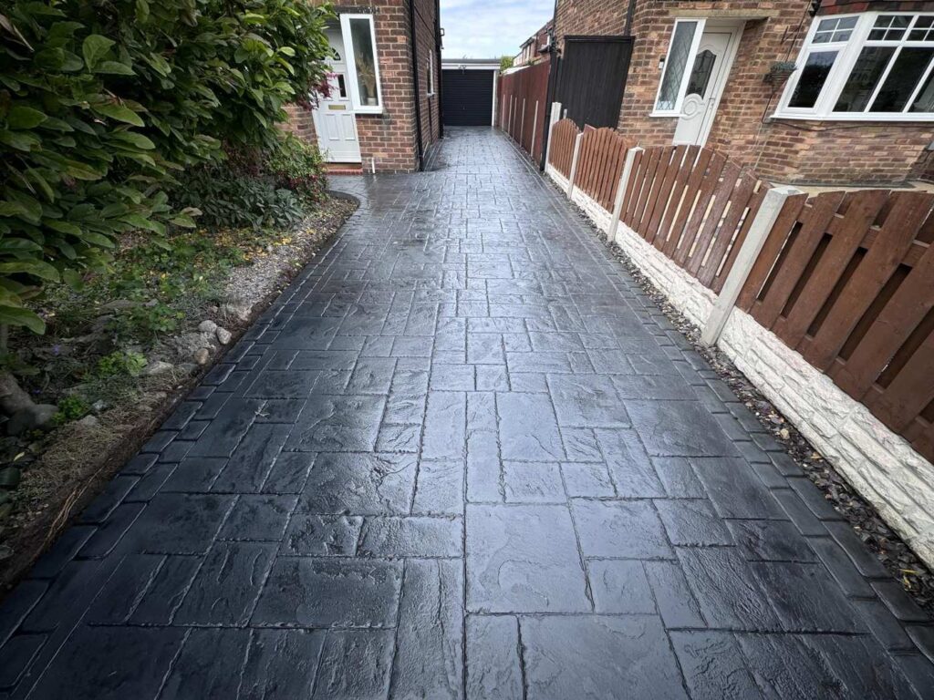 Dark slate pattern imprinted concrete driveway down the side of a house