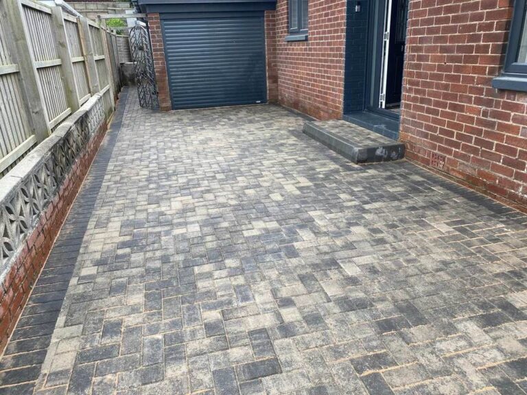 Grey block paved yard in front of a garage