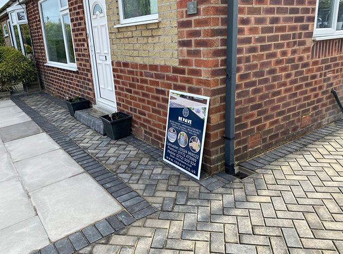 Grey herringbone block paved path beside a patio