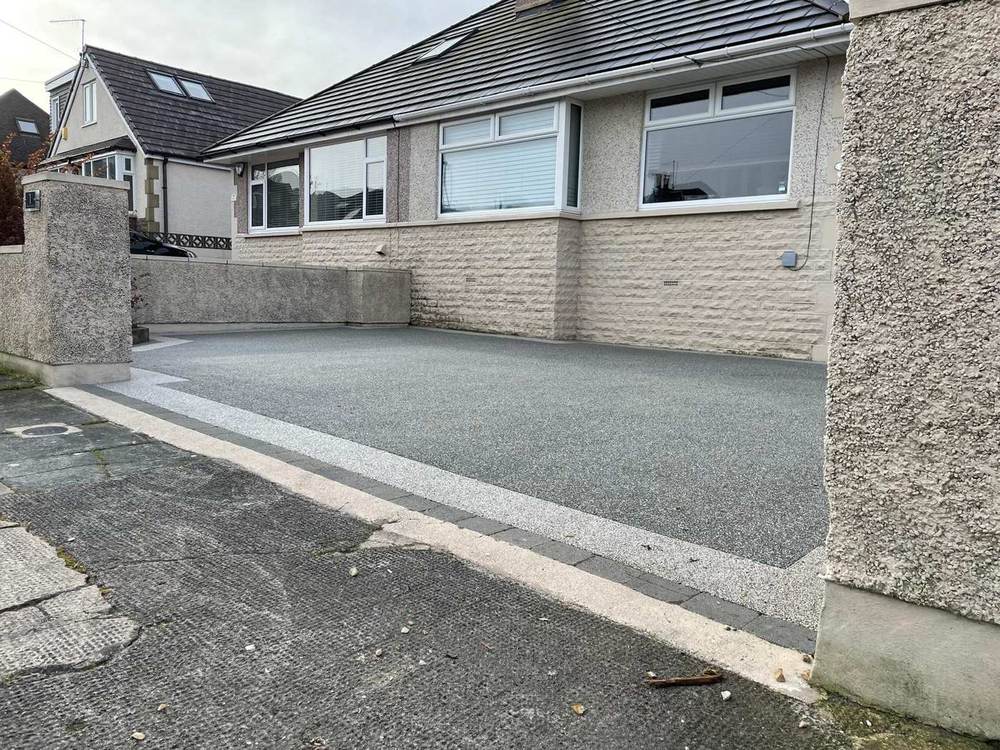 Grey resin bound driveway beside a stone wall