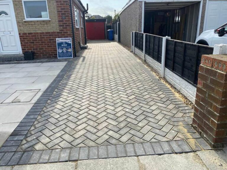Grey herringbone block paved driveway to a garage