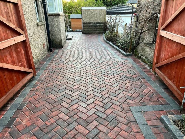 Red herringbone block path between timber gates
