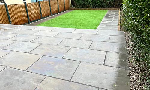 Porcelain patio leading to an artificial lawn