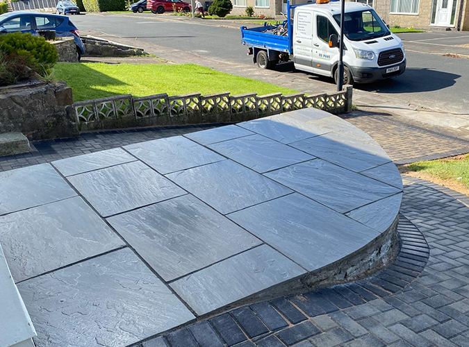 Raised porcelain patio with a curved block edge by the road