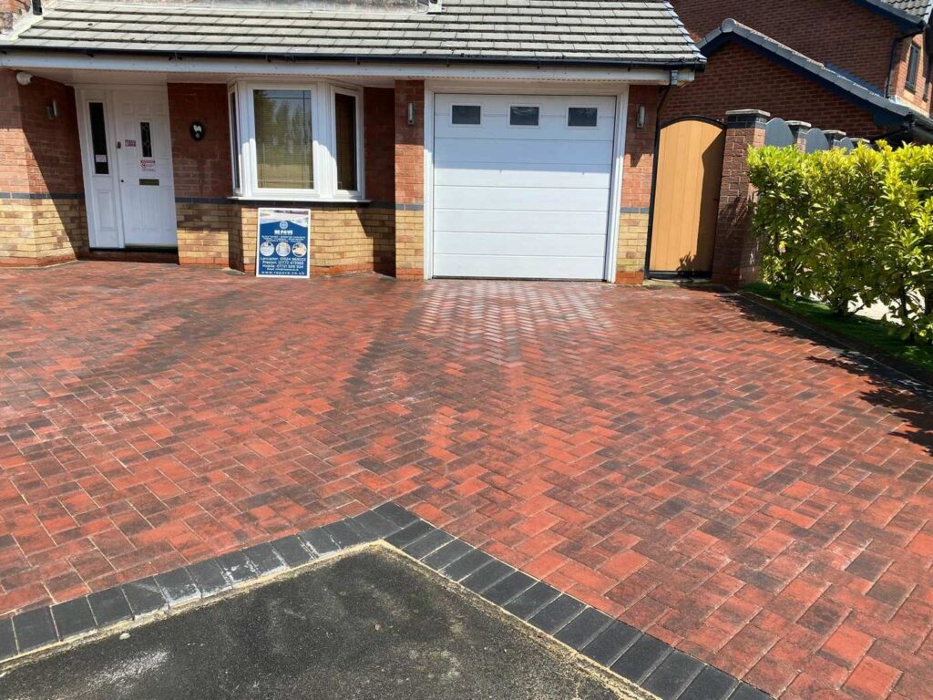 Red block paved driveway in front of a garage door