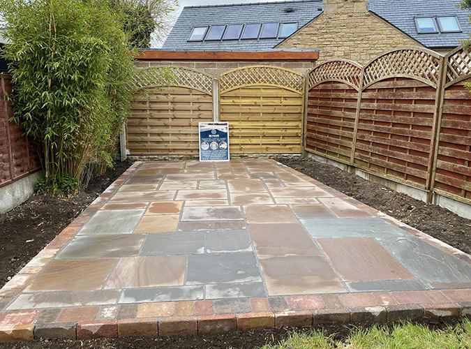 Indian sandstone patio in a fenced garden