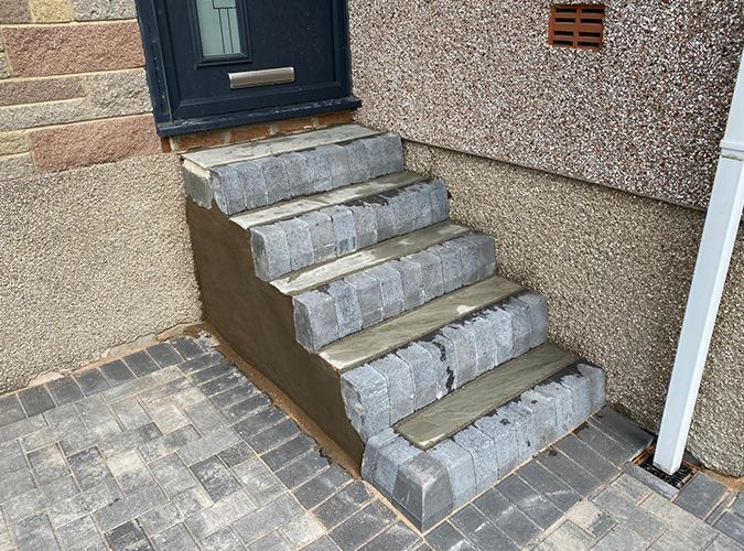 Stone steps above a block paved path