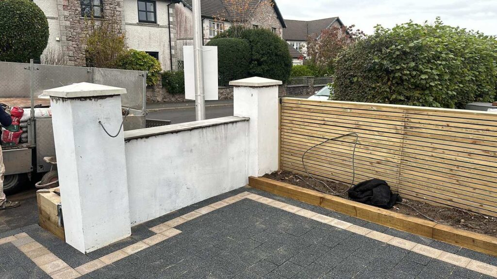 Tarmac driveway with a rendered wall and slatted fence