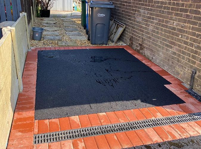 Tarmac yard with a red border and a drainage channel